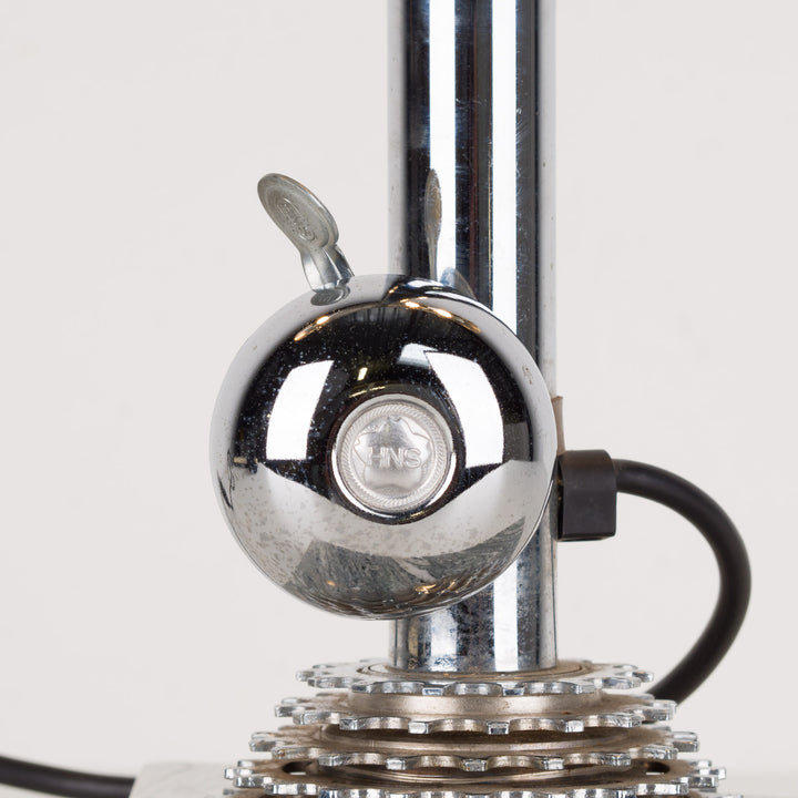 Fun metal table lamp with bicycle bell on a marble base.