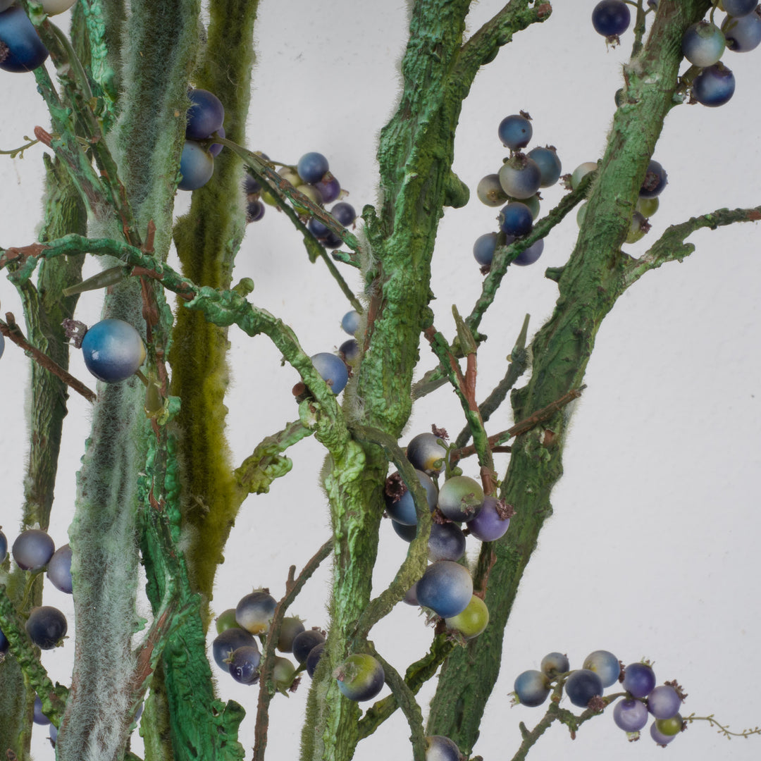 Large glass vase with beautiful branches of fake eucalyptus fruits in blue and green