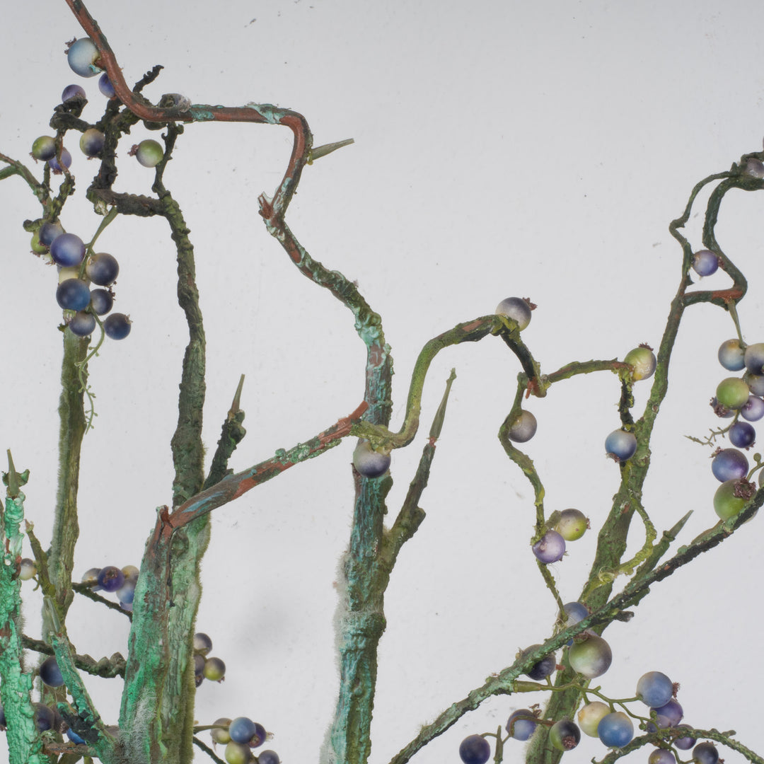 Large glass vase with beautiful branches of fake eucalyptus fruits in blue and green