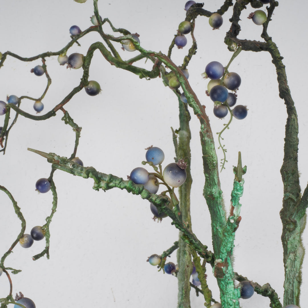 Large glass vase with beautiful branches of fake eucalyptus fruits in blue and green