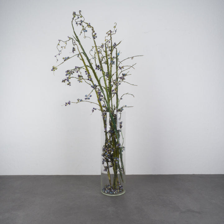 Large glass vase with beautiful branches of fake eucalyptus fruits in blue and green