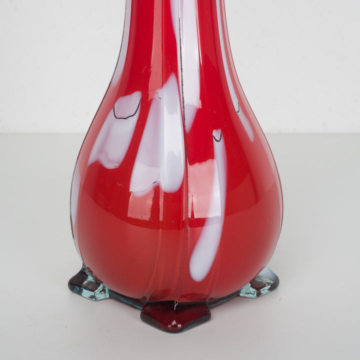 A red glass vase with white accents