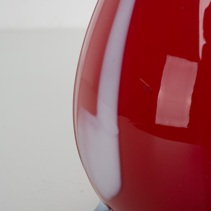 A red glass vase with white accents