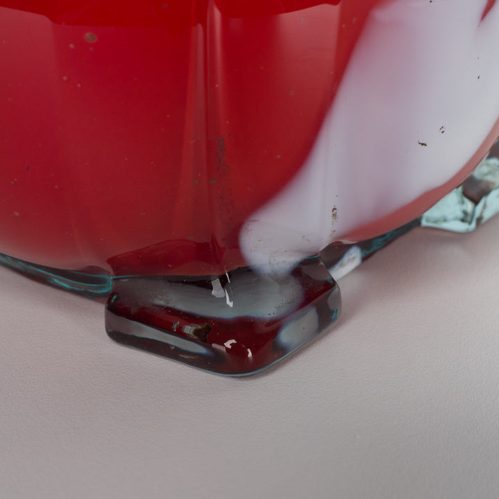 A red glass vase with white accents