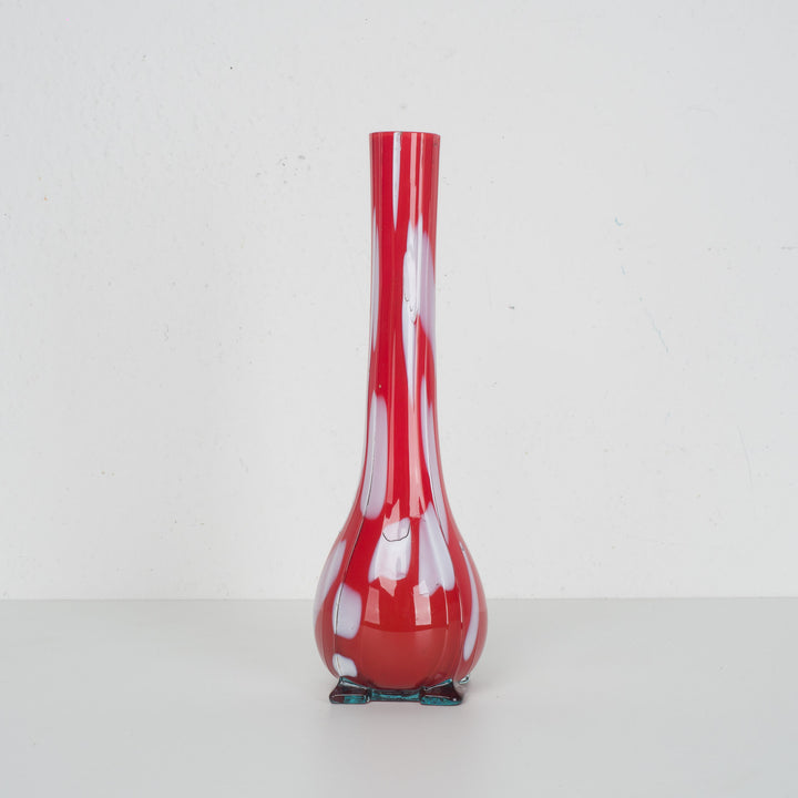 A red glass vase with white accents