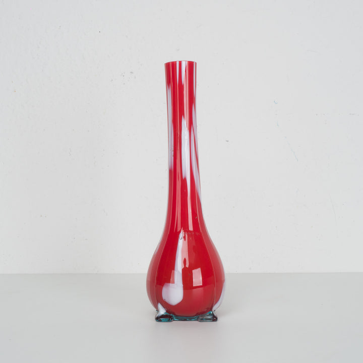 A red glass vase with white accents