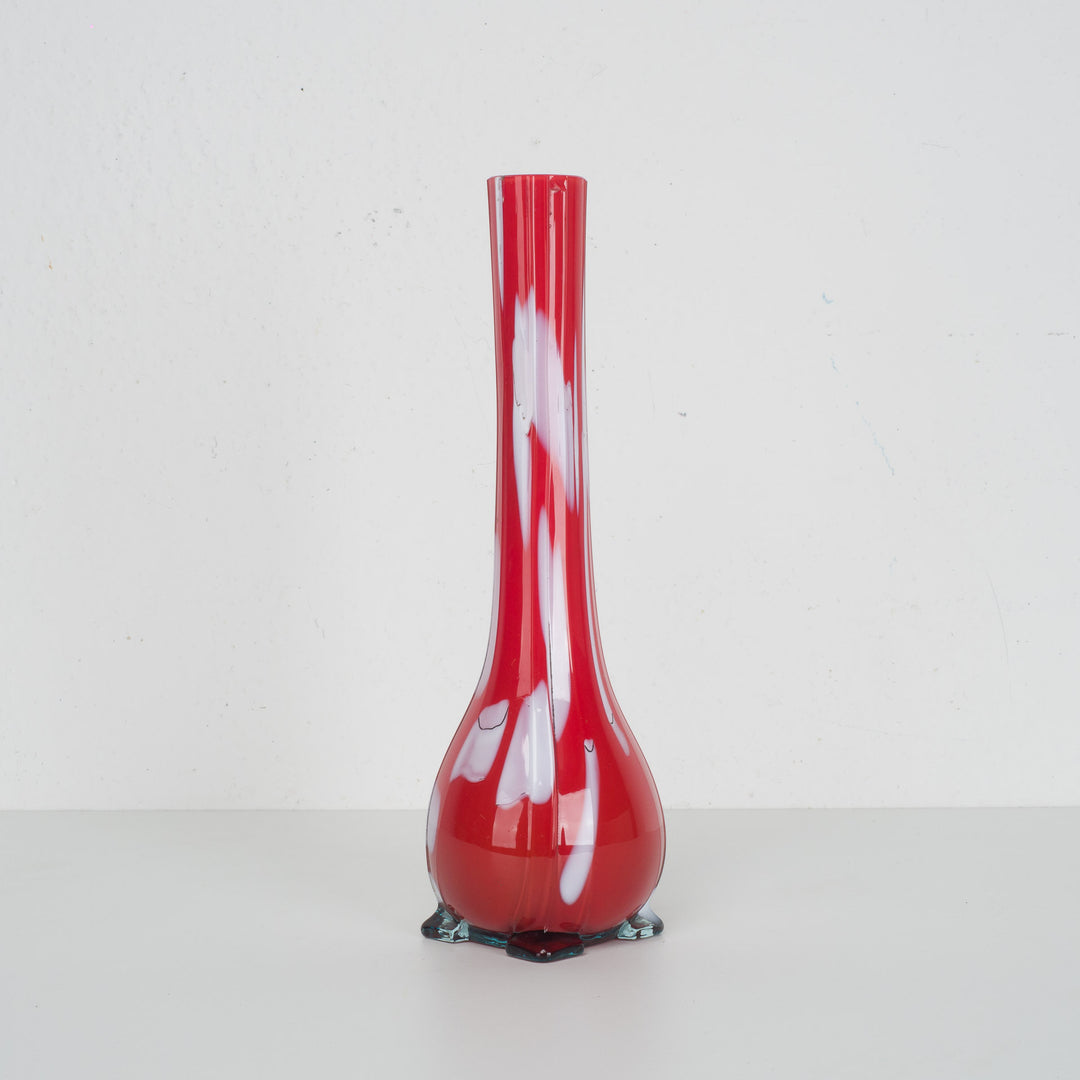 A red glass vase with white accents