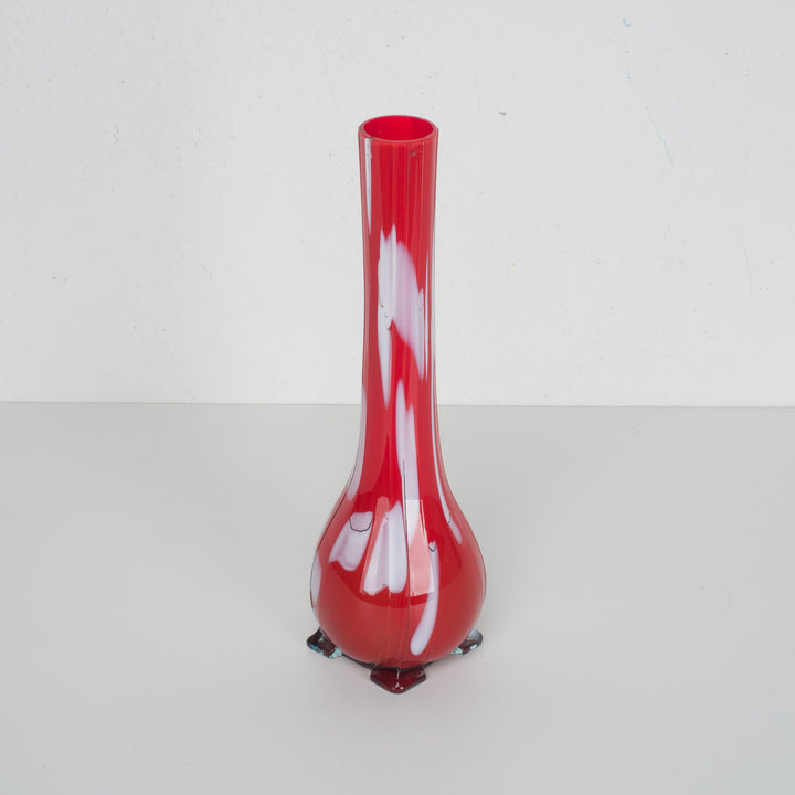 A red glass vase with white accents