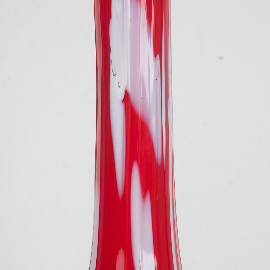 A red glass vase with white accents