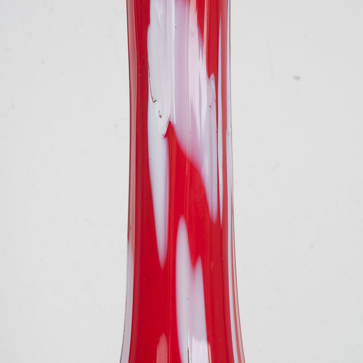 A red glass vase with white accents