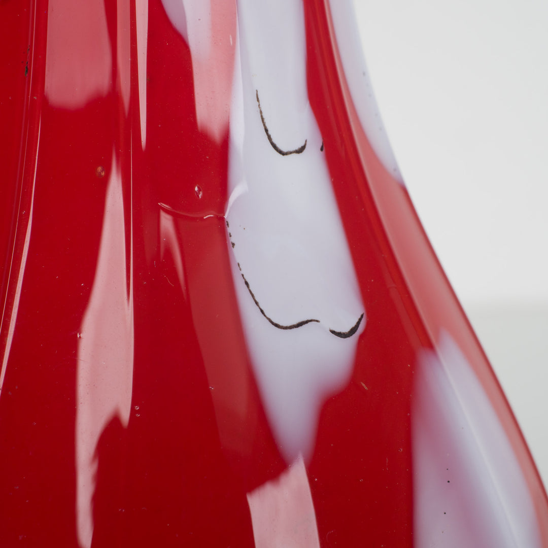 A red glass vase with white accents