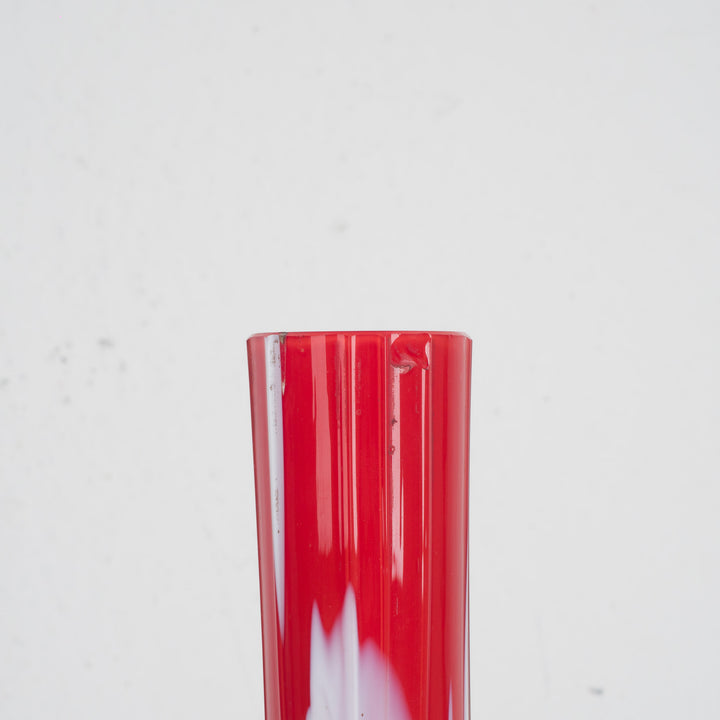 A red glass vase with white accents
